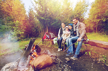 Image showing happy family sitting on bench at camp fire