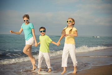 Image showing Three happy children running on the beach at the day time.