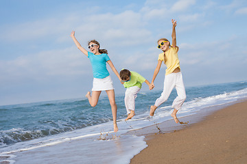 Image showing Three happy children running on the beach at the day time.