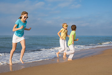 Image showing Three happy children running on the beach at the day time.