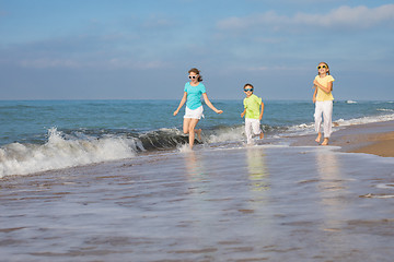 Image showing Three happy children running on the beach at the day time.