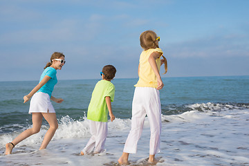 Image showing Three happy children running on the beach at the day time.