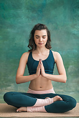 Image showing Studio shot of a young woman doing yoga exercises on green background