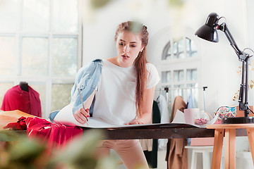 Image showing Fashion designers working in studio sitting on the desk