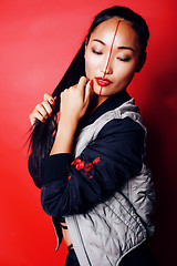 Image showing young pretty asian girl posing cheerful on red background, fashion style makeup and hair, lifestyle modern orient people concept