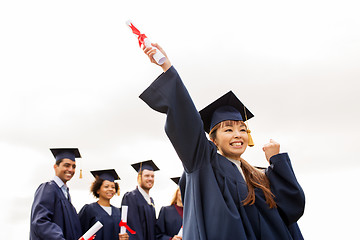 Image showing happy students in mortar boards with diplomas