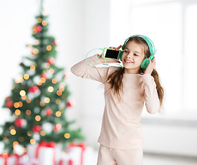 Image showing girl with smartphone and headphones at christmas