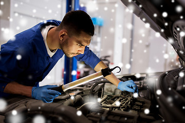 Image showing mechanic man with lamp repairing car at workshop