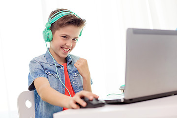 Image showing boy in headphones playing video game on laptop