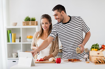 Image showing happy couple with tablet pc cooking food at home