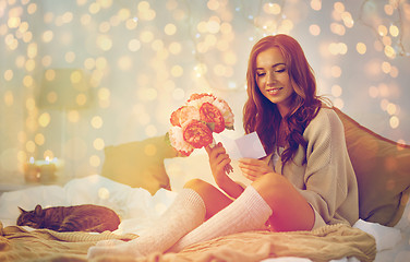 Image showing happy woman with flowers and greeting card at home