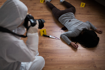 Image showing criminalist photographing dead body at crime scene