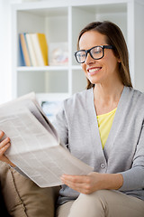 Image showing woman in glasses reading newspaper at home