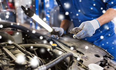 Image showing mechanic man with pliers repairing car at workshop