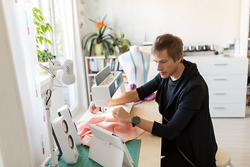 Image showing fashion designer with tablet pc sewing at studio