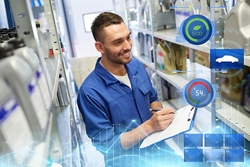 Image showing smiling auto mechanic with clipboard at car shop