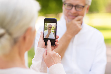 Image showing old woman photographing man by smartphone in park