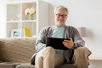 Image showing senior man with tablet pc sitting on sofa at home