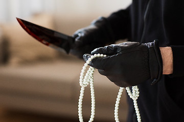 Image showing criminal with knife and jewelry at crime scene