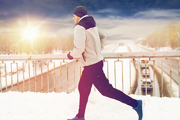 Image showing man running along snow covered winter bridge road