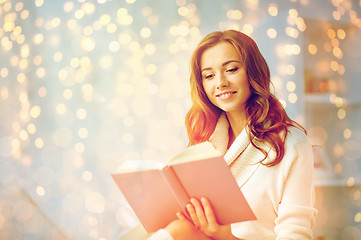 Image showing happy young woman reading book at home