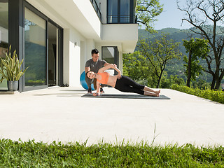 Image showing woman with personal trainer doing morning yoga exercises