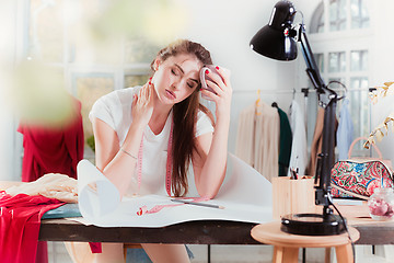 Image showing Fashion designers working in studio sitting on the desk