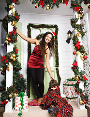 Image showing happy family on Christmas in red hats waiting gests and smiling outdoor