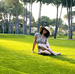 Image showing young pretty woman in hat sitting on green grass, happy smiling lifestyle people concept