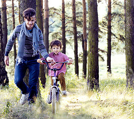 Image showing father learning his son to ride on bicycle outside in park