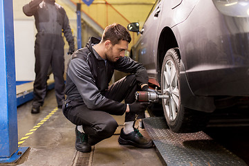 Image showing auto mechanic with screwdriver changing car tire