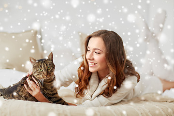 Image showing happy young woman with cat lying in bed at home