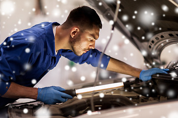 Image showing mechanic man with lamp repairing car at workshop