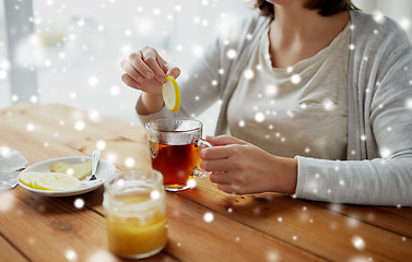 Image showing close up of woman adding honey to tea with lemon