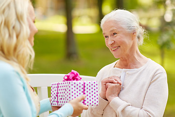 Image showing daughter giving present to senior mother at park