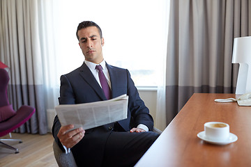Image showing businessman reading newspaper at hotel room