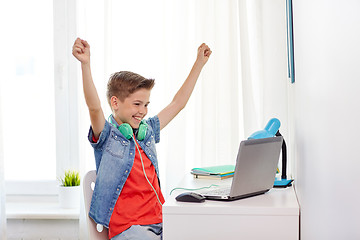 Image showing boy with headphones playing video game on laptop