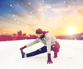 Image showing man exercising and stretching leg on winter bridge