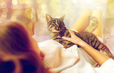 Image showing happy young woman with cat lying in bed at home