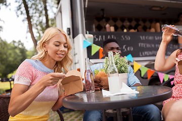 Image showing happy friends with drinks eating at food truck