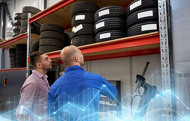 Image showing mechanic and man choosing tires at car shop