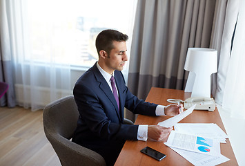 Image showing businessman with papers working at hotel room