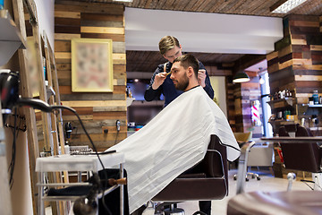 Image showing man and barber cutting hair at barbershop