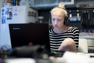 Image showing Adult woman in her casual home clothing working and studying remotely from her small flat late at night.