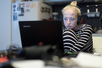 Image showing Adult woman in her casual home clothing working and studying remotely from her small flat late at night.