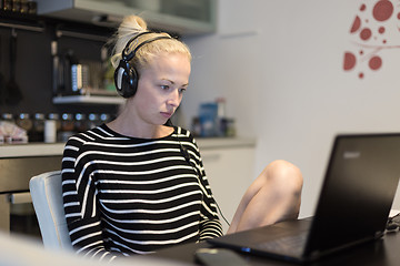 Image showing Adult woman in her casual home clothing working and studying remotely from her small flat late at night.