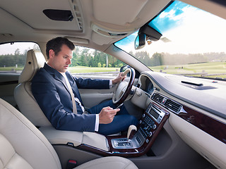 Image showing Businessman using cell phone and texting while driving not paying attention to the road.