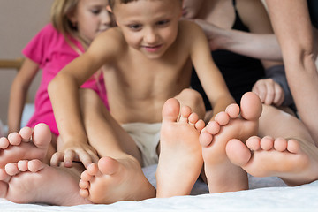 Image showing Happy brother and sisters  sitting on the bed barefoot