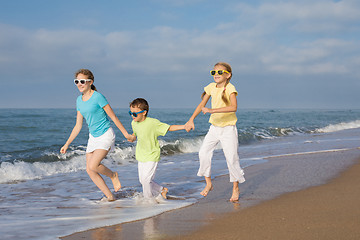 Image showing Three happy children running on the beach at the day time.