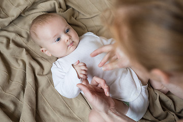 Image showing mom dresses the baby on the bed